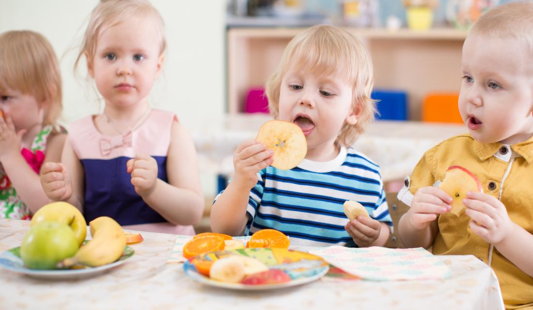 Kindergruppe isst Obst im Kindergarten Esszimmer