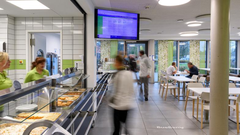 Gäste stehen an der Essensausgabe der Kantine