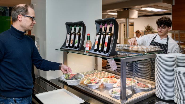 Ein Gast nimmt sich eine Schüssel Salat