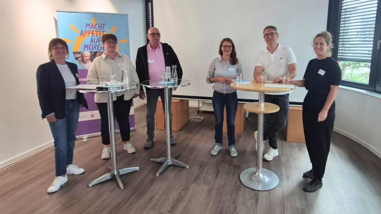 Teilnehmende und Referent:innen an Stehtischen
